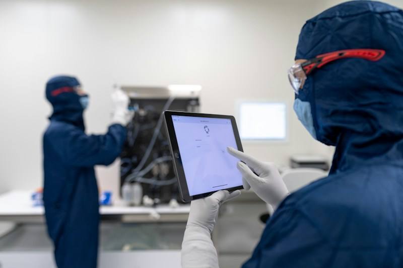 Technicians in lab coats reviewing results on a screen, representative image