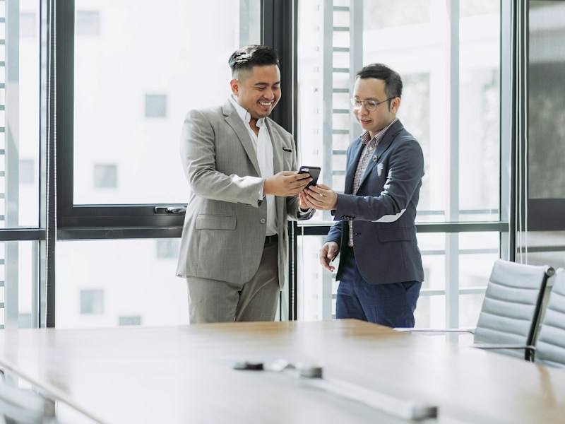 Two colleagues reviewing a phone in an office, representative image