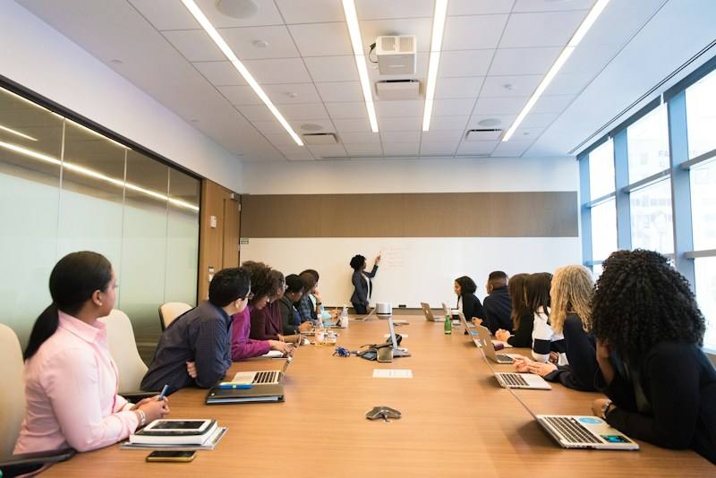 Team listening to a colleague in a meeting room, representative image