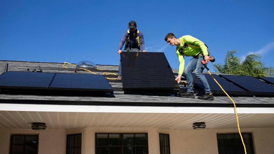 Two installers working together on a roof, representative image
